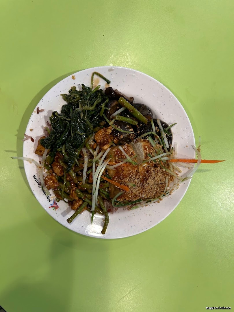 A plate of vegetarian food with various vegetables and toppings on a green table.