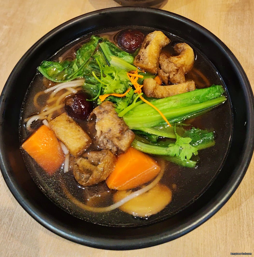 A bowl of vegetarian noodle soup with vegetables and tofu.