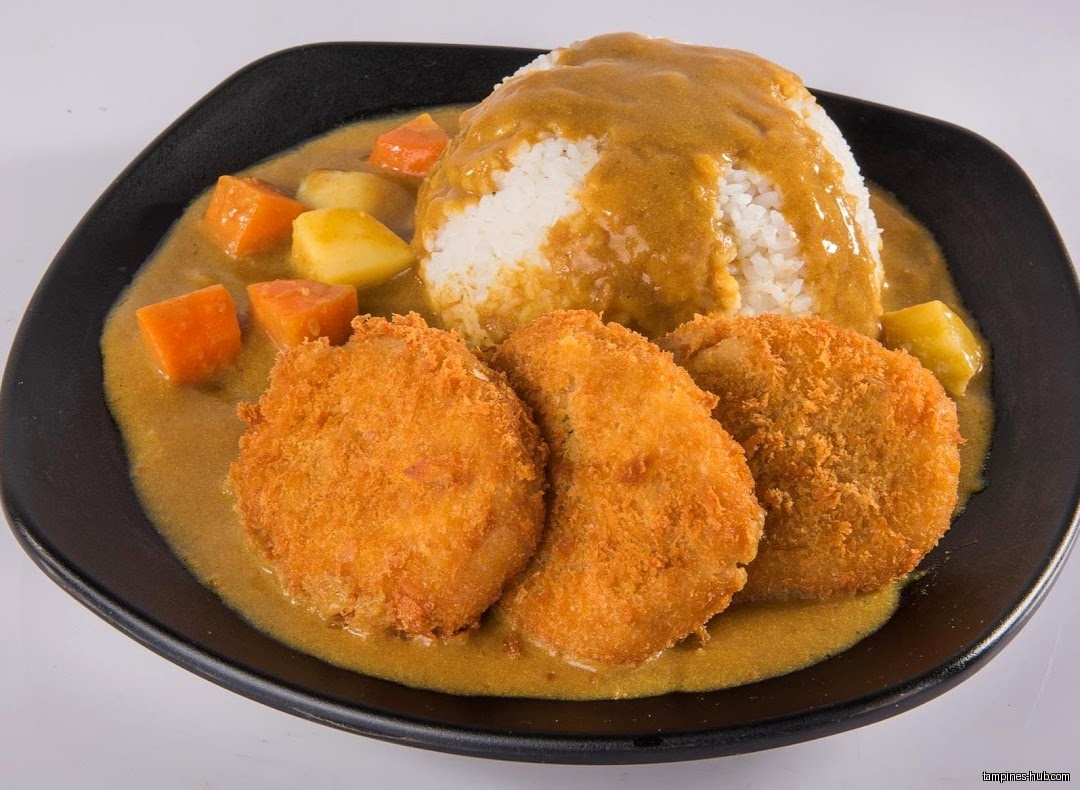 Japanese curry with rice, fried cutlets, carrots, and potatoes on a plate.