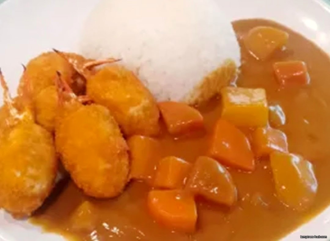 A plate of Japanese curry with rice, fried shrimp, and vegetables.