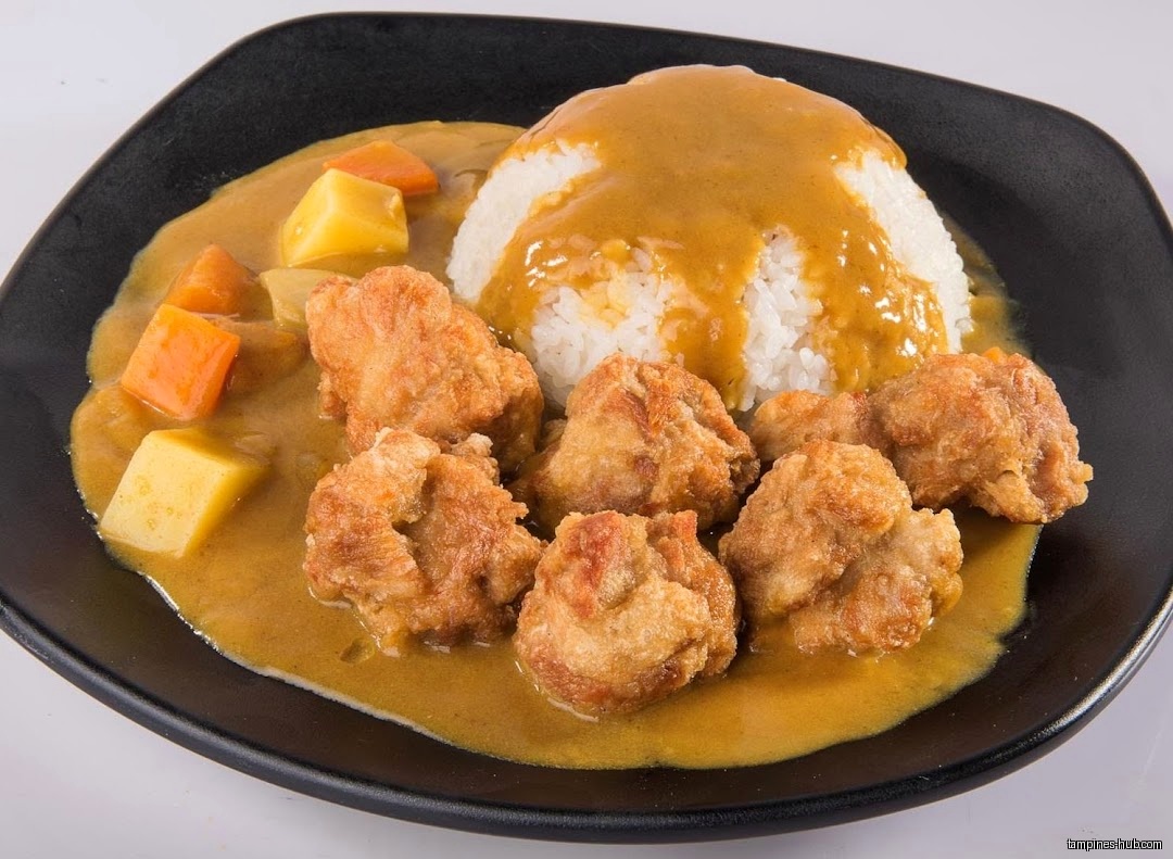 A plate of Japanese curry with rice, fried chicken, and vegetables.