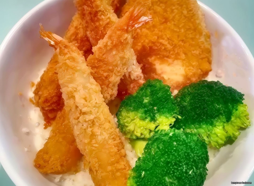 A bowl of Japanese curry with fried shrimp, fish, and broccoli.