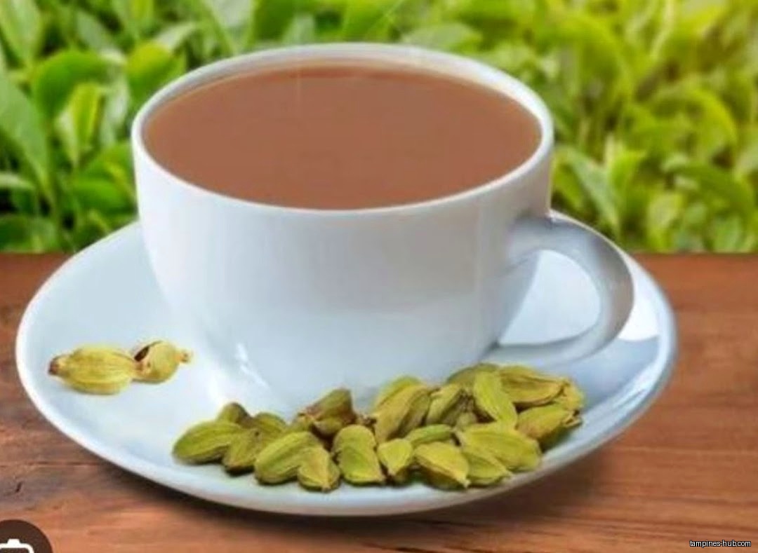 A cup of tea with cardamom pods on a saucer.