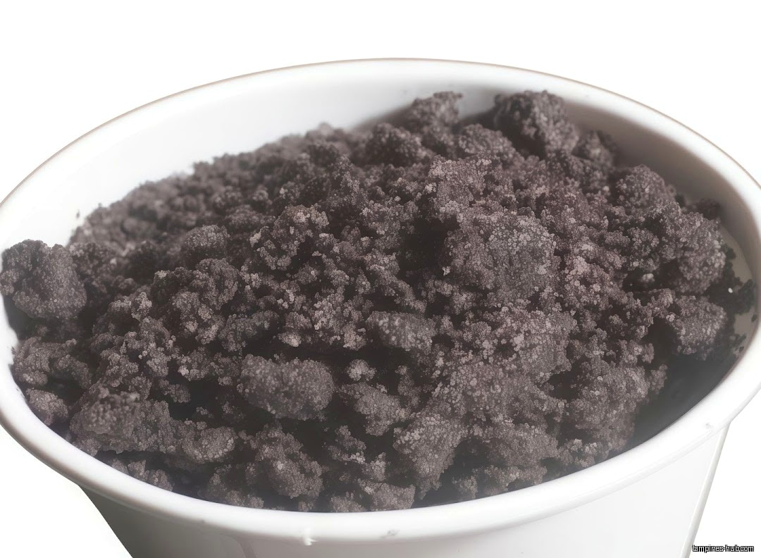 A white bowl filled with dark, crumbly material, possibly a food item.