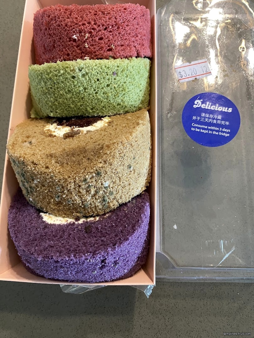 A box of colorful swiss rolls from KenJinn Bakery with a price sticker.