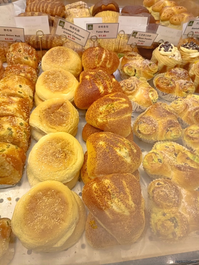 A display case filled with various types of baked goods and price tags.