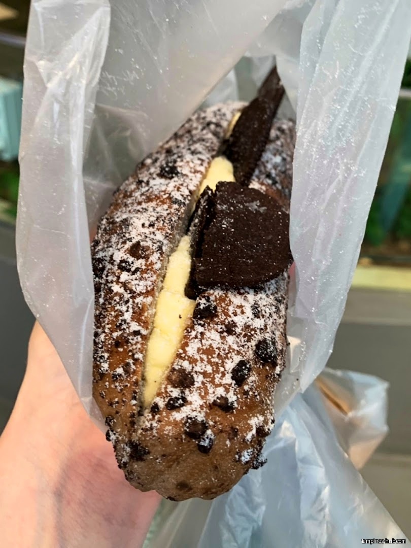 A chocolate chip bread roll with cream and chocolate cookies in a bag.