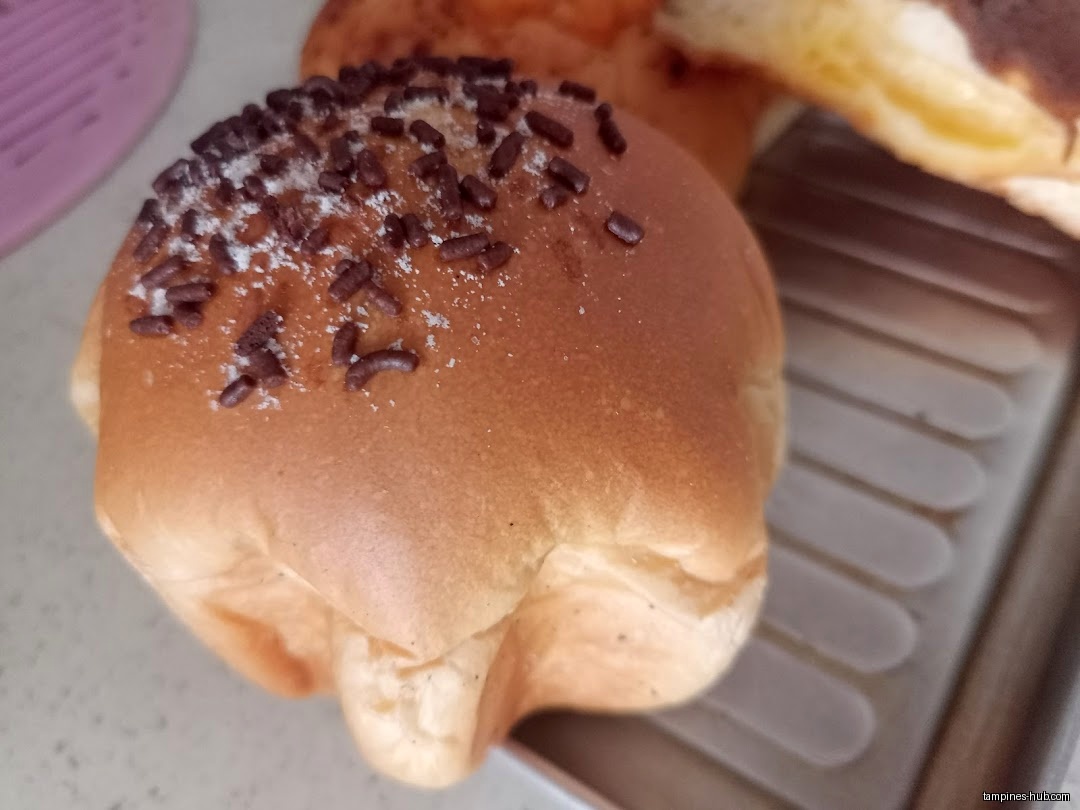 Close-up of a bun with chocolate sprinkles on a metal rack.