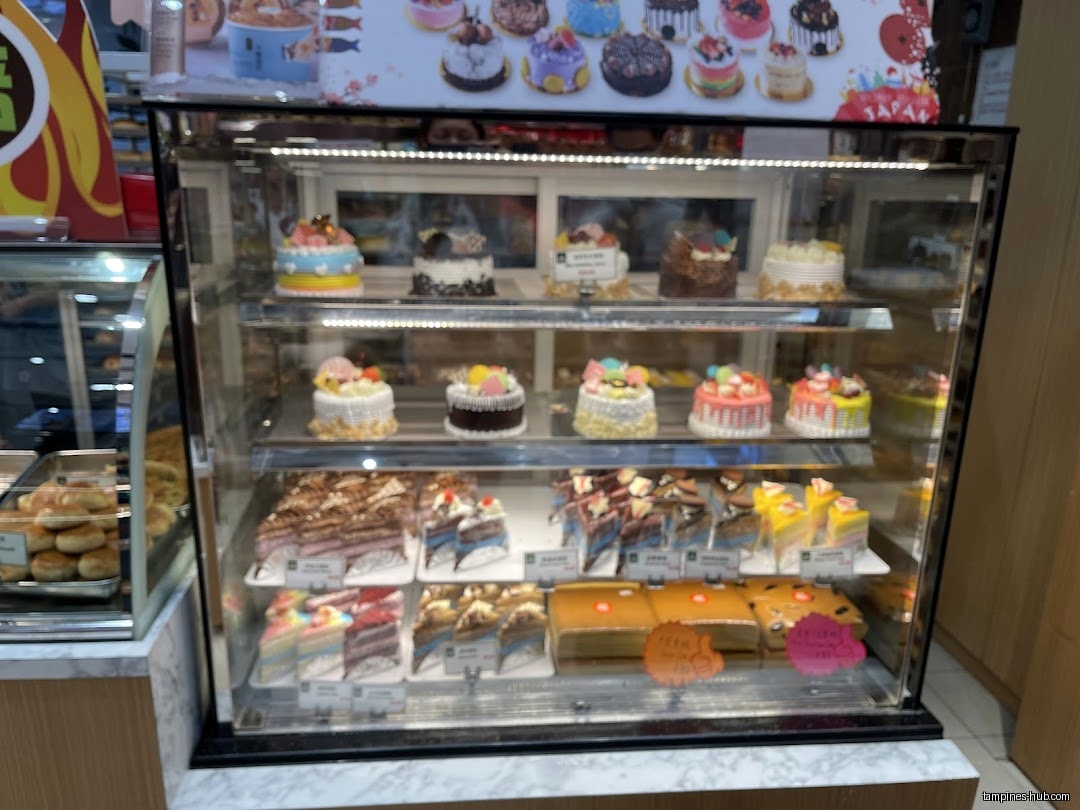 A display case filled with various cakes and pastries at KenJinn Bakery.