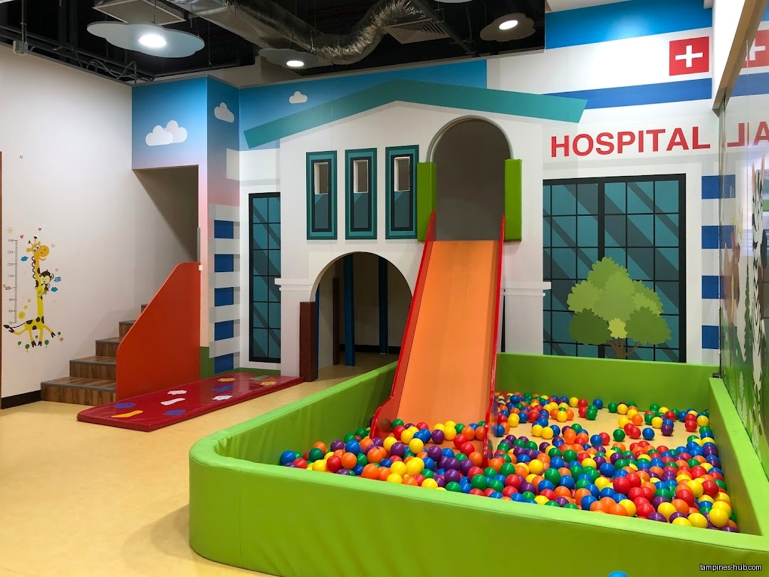Indoor playground with a slide, ball pit, and hospital-themed backdrop.