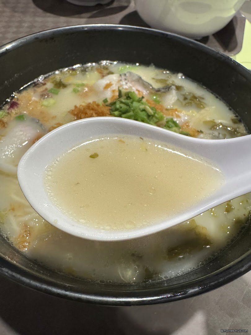 A bowl of soup with a spoon holding some of the broth.
