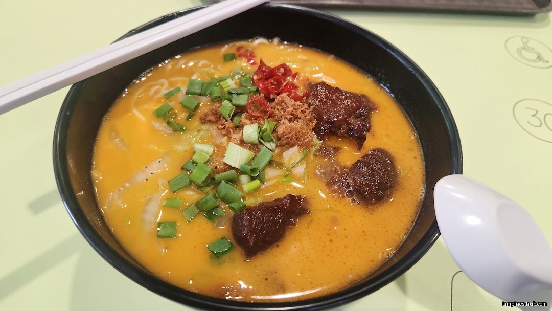 A bowl of Lobster King Pao Fan soup with meat and green onions.