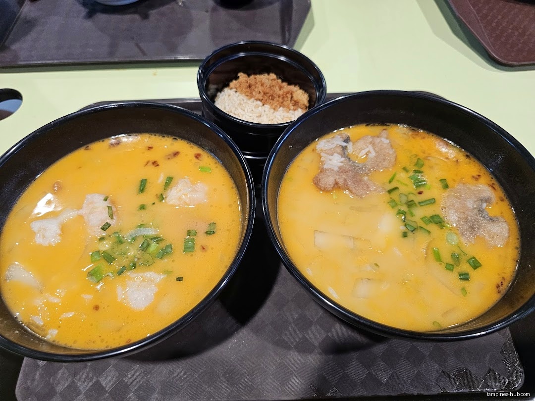 Two bowls of Lobster King Pao Fan soup with rice on a tray.