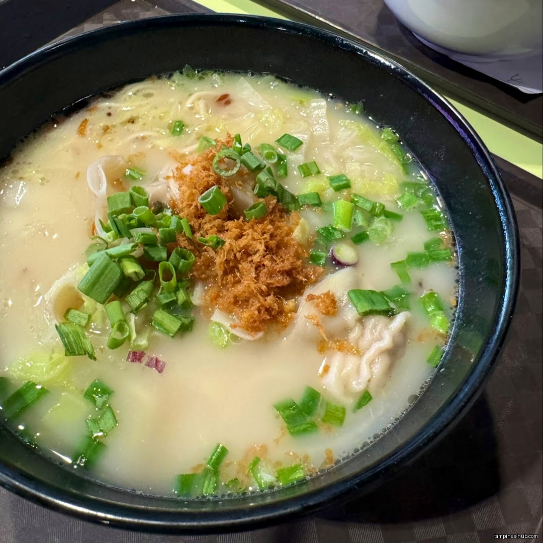A bowl of Lobster King Pao Fan soup with green onions and toppings.
