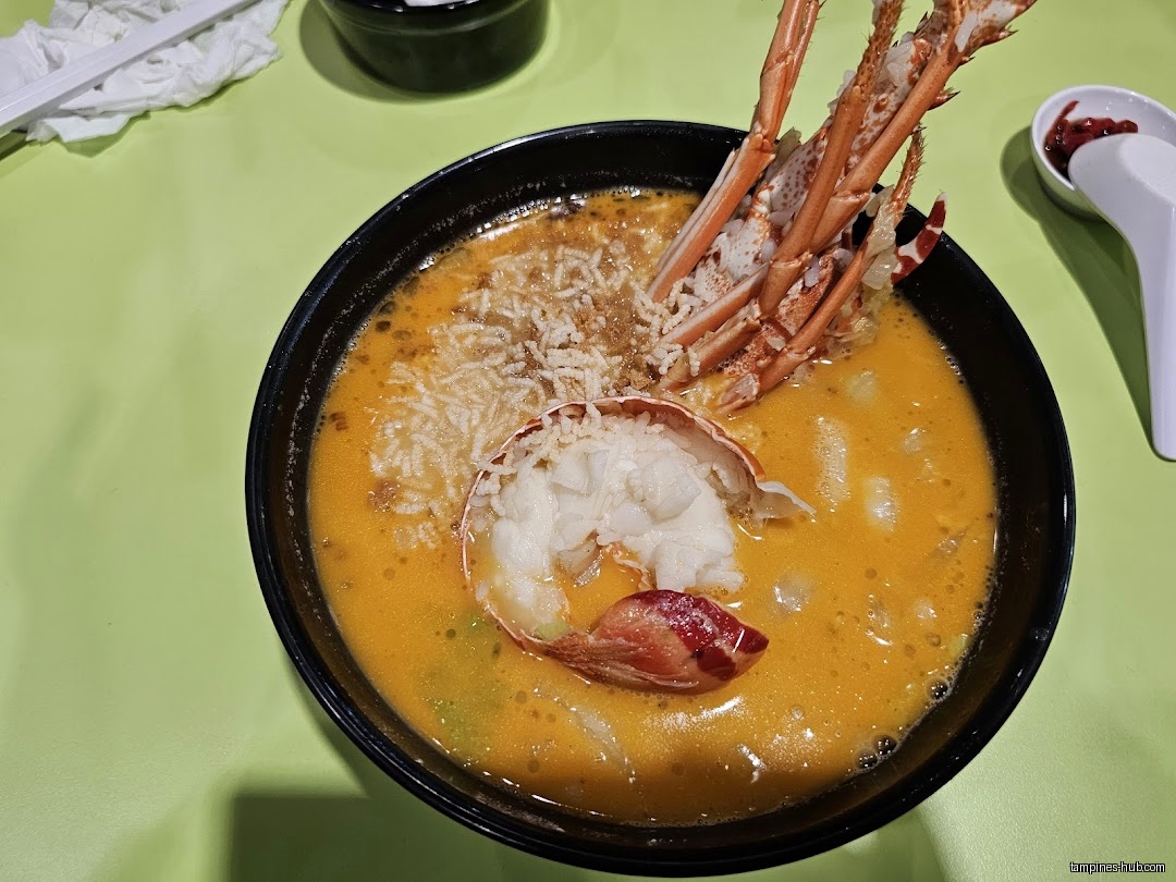 A bowl of Lobster King Pao Fan with lobster meat and broth.