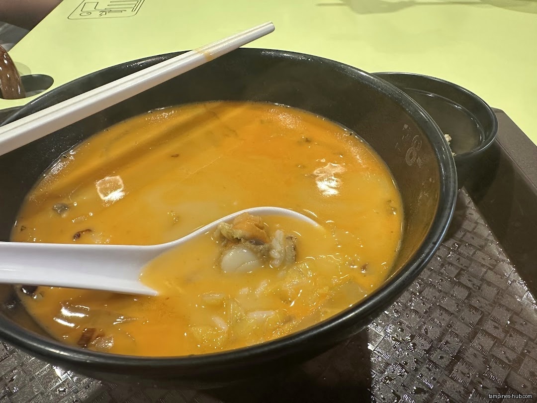 A bowl of Lobster King Pao Fan soup with chopsticks and a spoon.