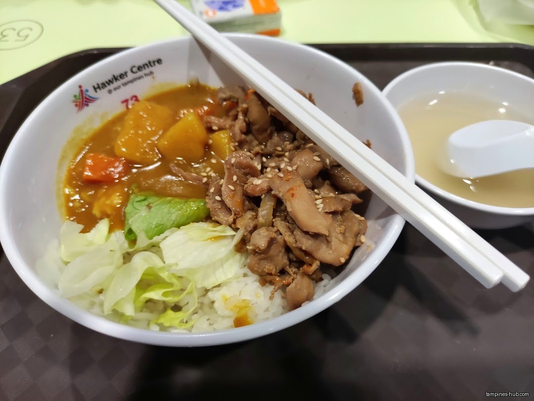 The image shows a bowl of curry rice with meat and a side of soup.