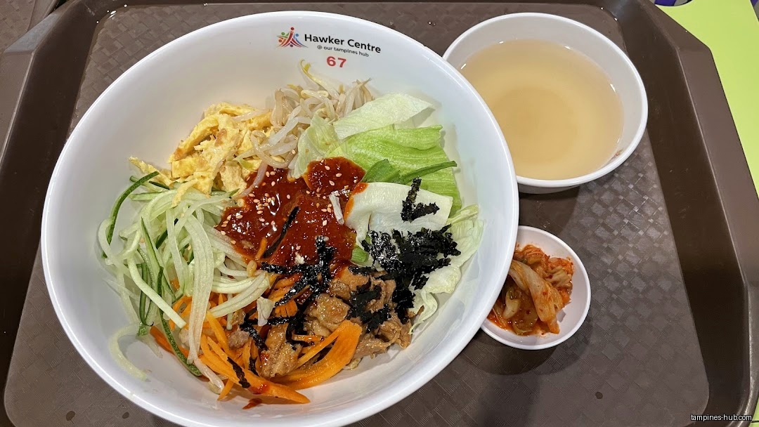 A bowl of bibimbap with soup and kimchi on a tray.
