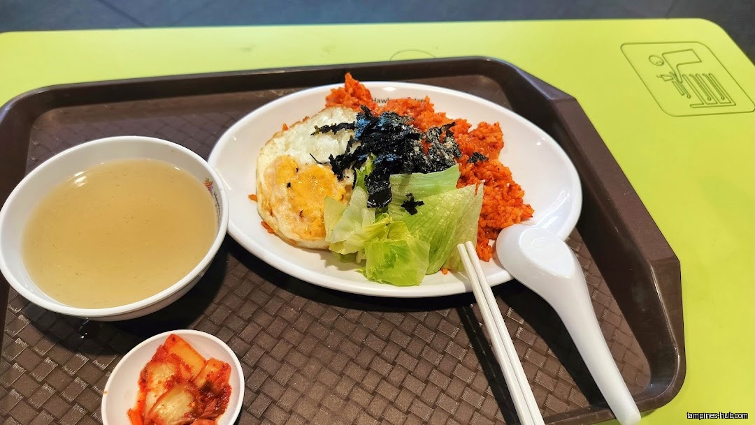 A tray with a plate of food, soup, kimchi, and utensils.