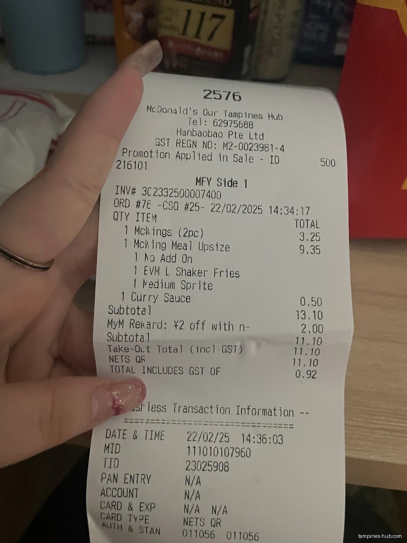 A hand holds a McDonald's receipt showing items purchased and total cost.