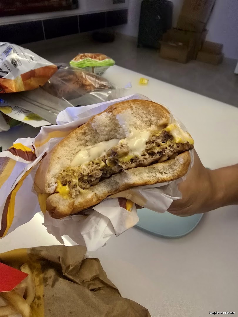 A half-eaten McDonald's burger is held with fries and other food items.