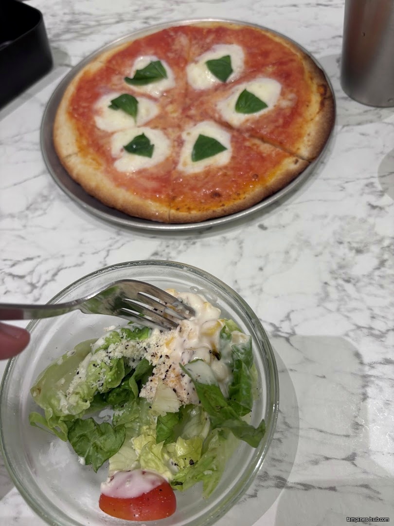 Pizza and salad are on a table, with a fork in the salad.