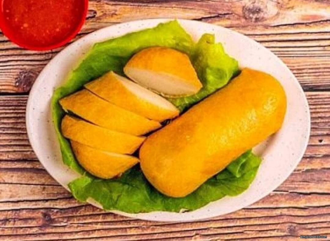 A plate of sliced fishcake with lettuce and a side of chili sauce.