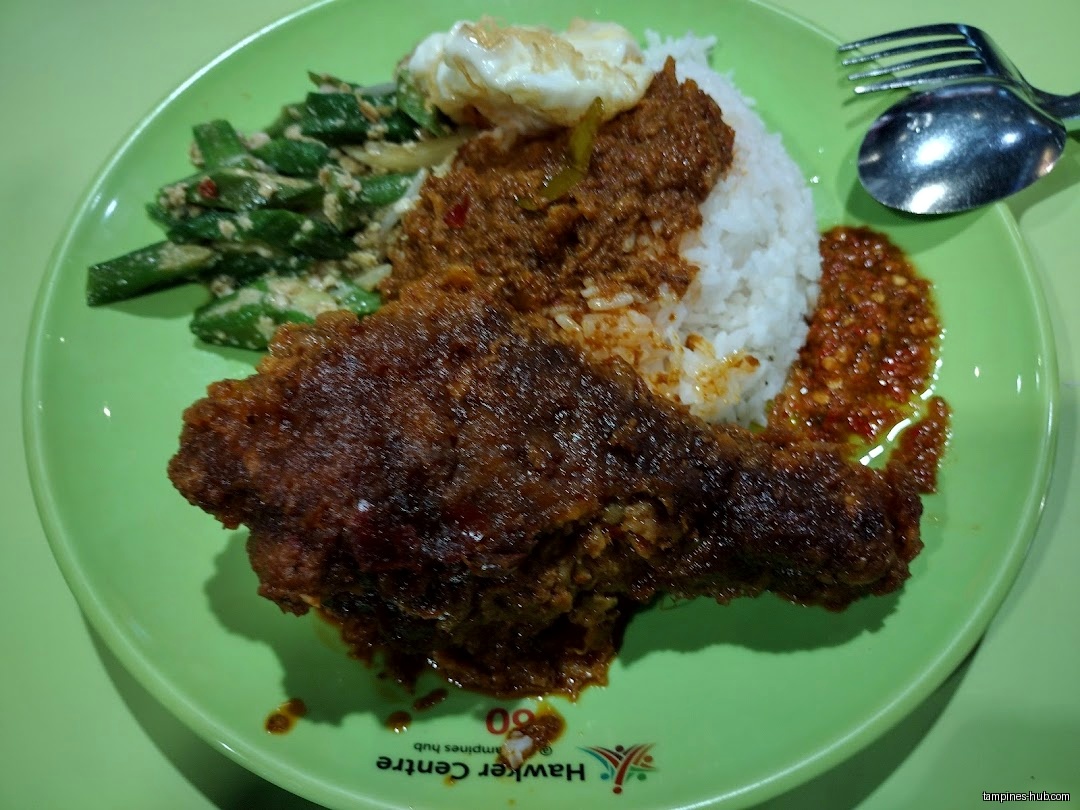 A plate of rice, fried chicken, vegetables, egg, and chili sauce.