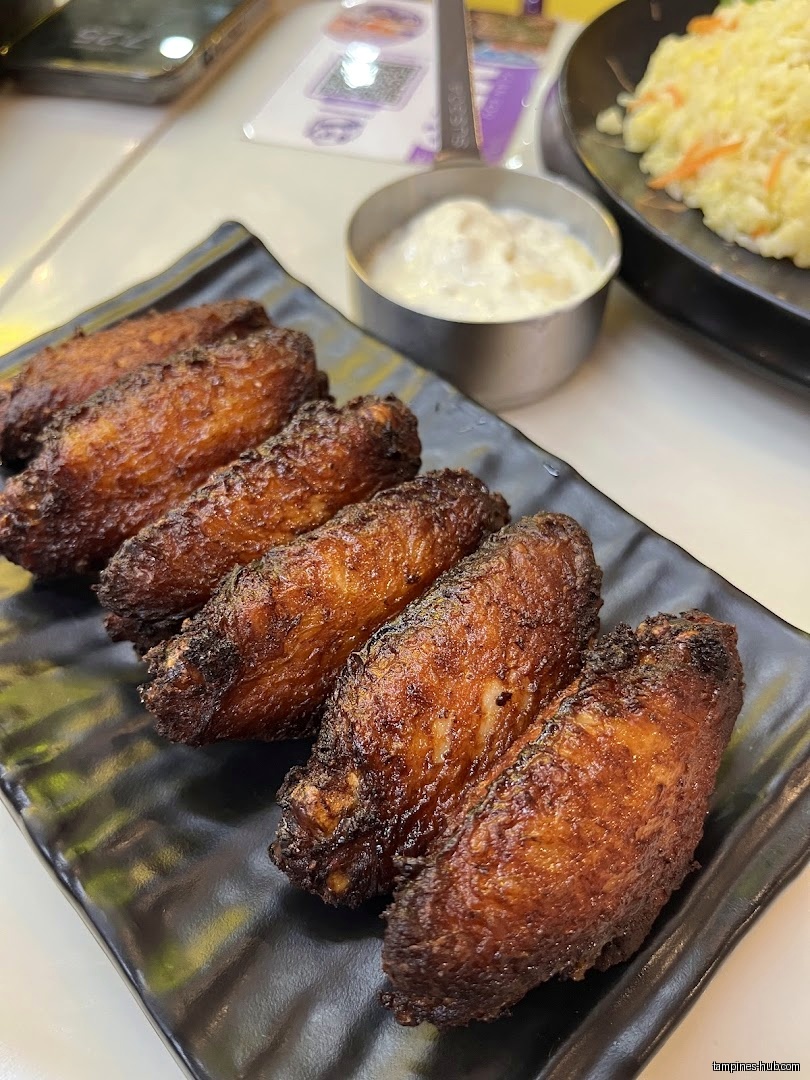 A plate of fried chicken wings with a side of dipping sauce.