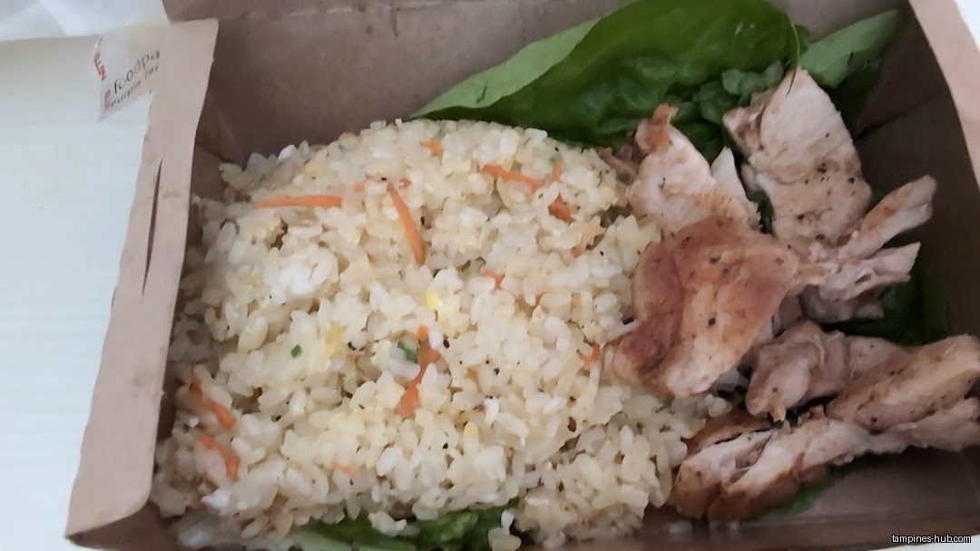 A takeout box contains fried rice, lettuce, and sliced grilled chicken.