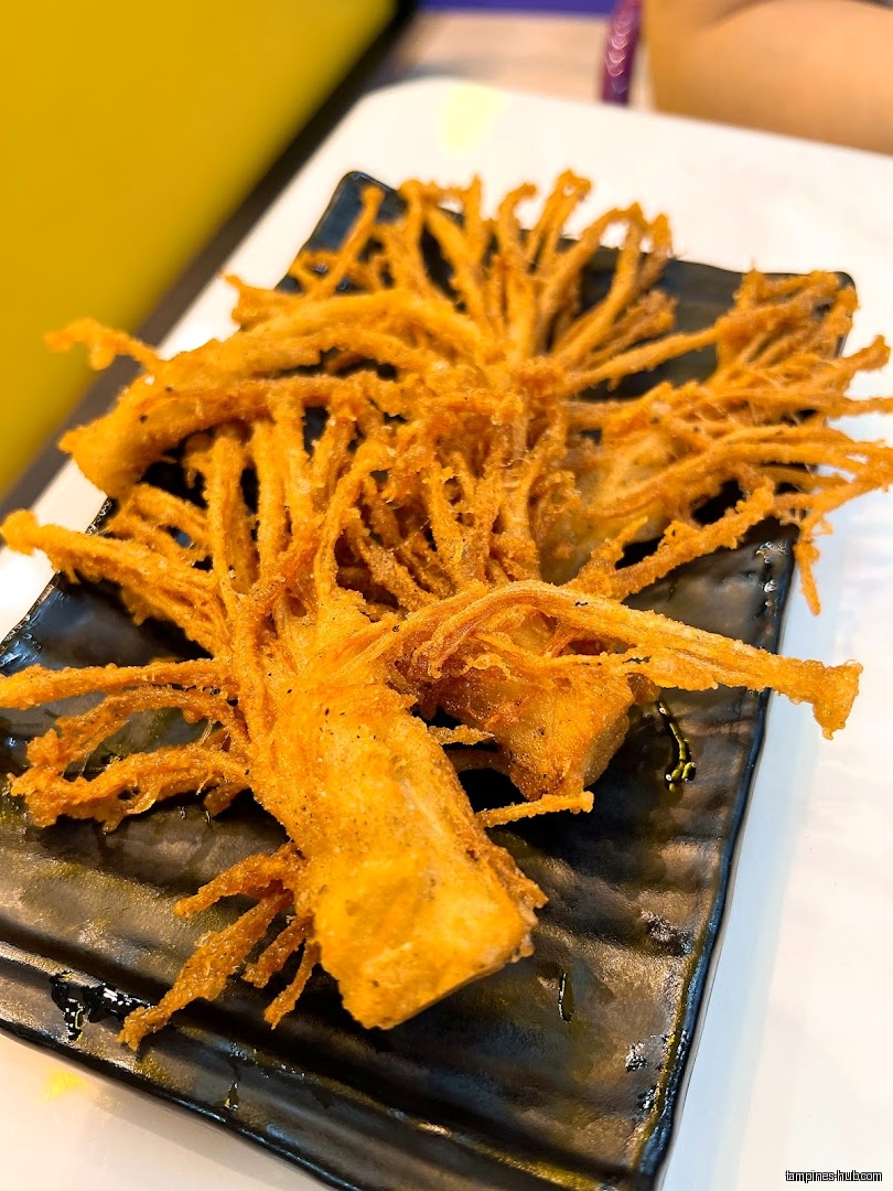 A black plate holds fried enoki mushrooms, likely a menu item.