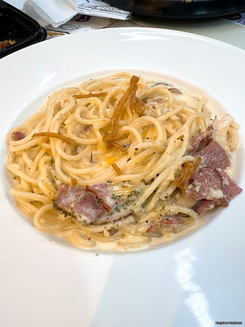 A plate of creamy spaghetti with bacon and fried onions is shown.