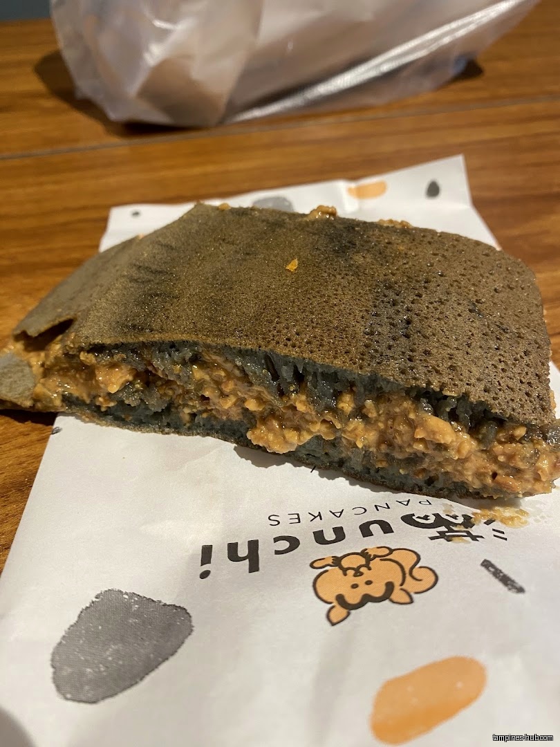 A cut pancake with peanut filling sits on Munchi Pancakes branded paper.