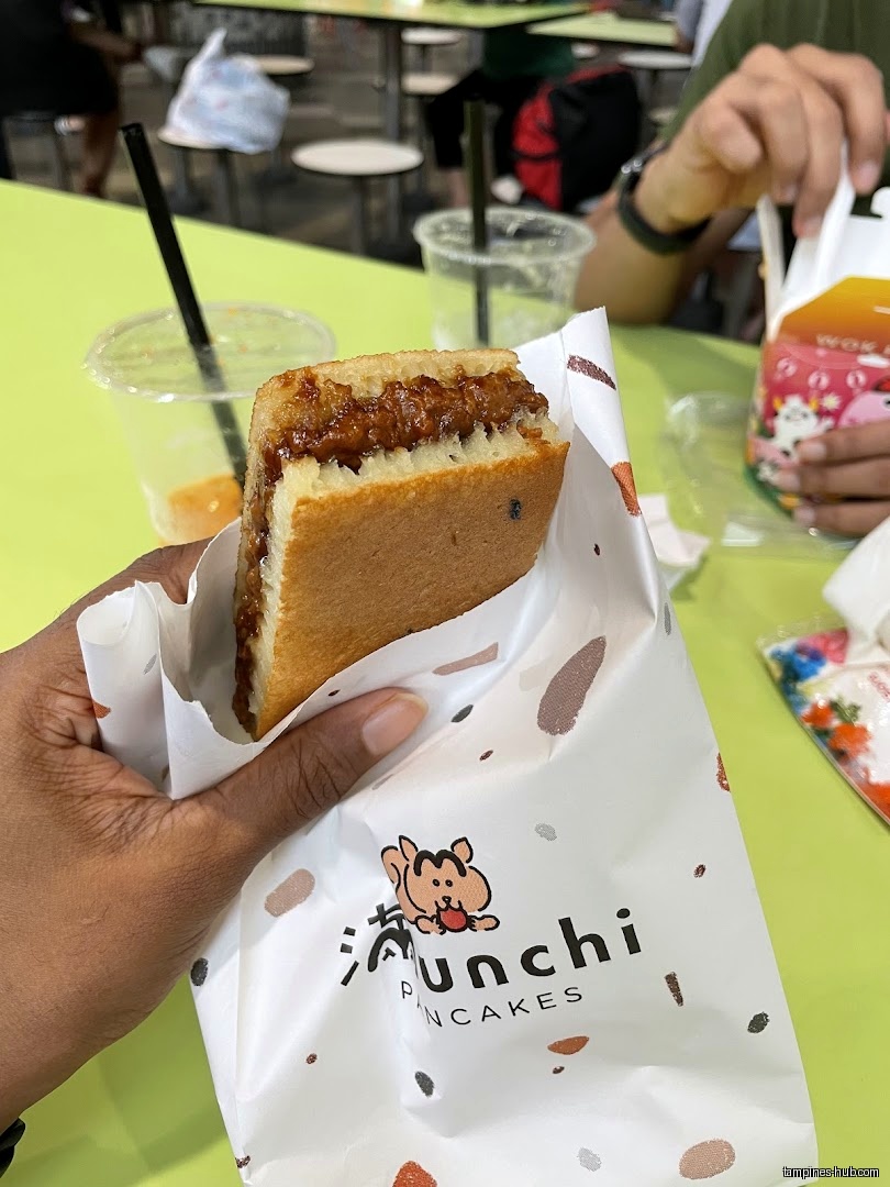 A Munchi Pancakes pancake is held in its branded wrapper.
