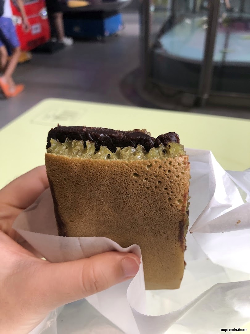 A hand holds a Munchi pancake with chocolate filling in paper.