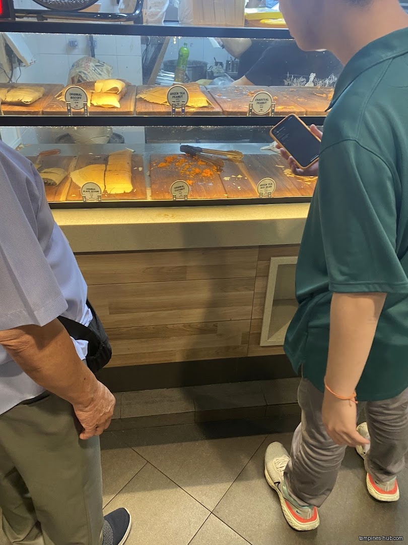 Customers view pancakes with different toppings displayed in a glass case.