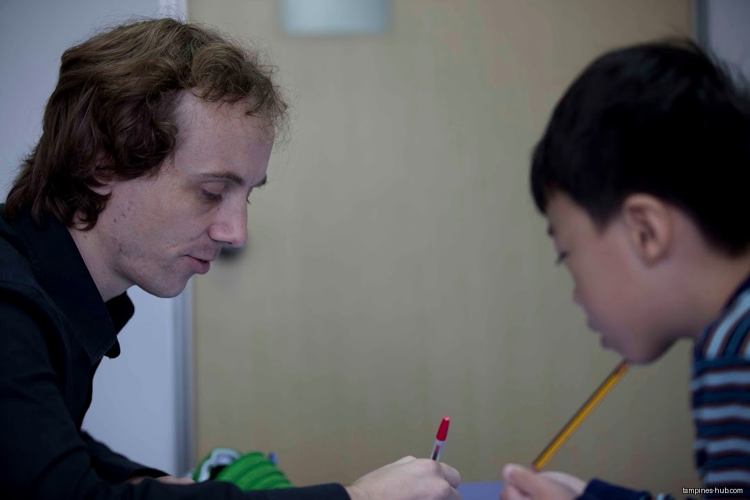 A teacher helps a student with his work at a desk.
