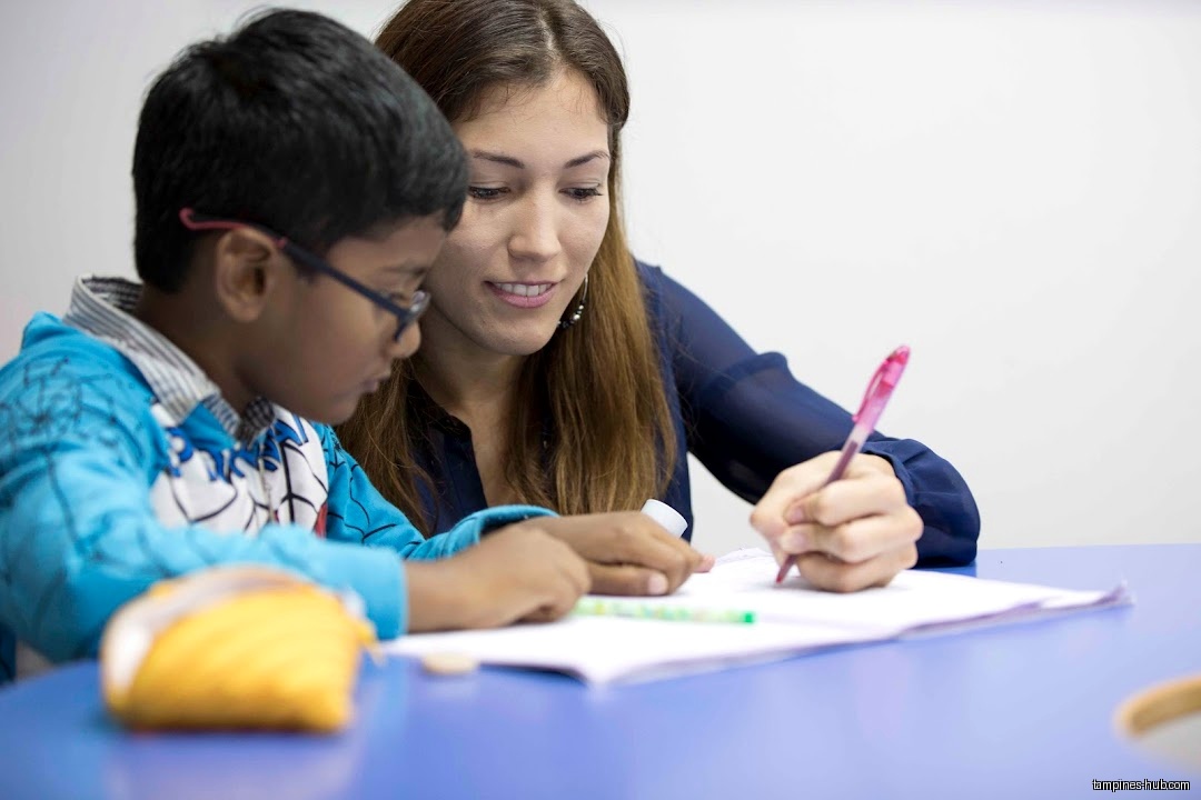 A teacher helps a student with his schoolwork at a desk.