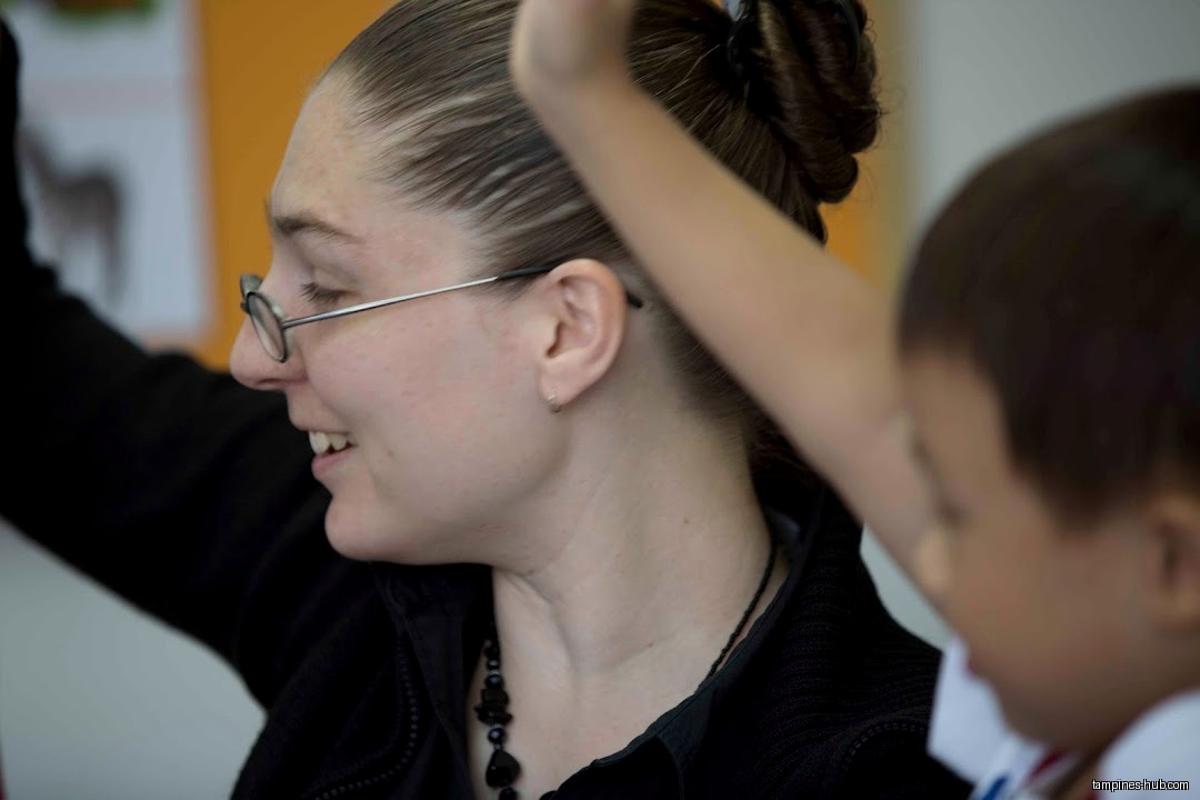 A teacher interacts with a young student in a classroom setting.