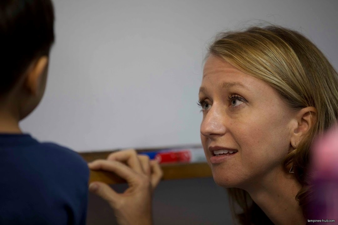 A teacher interacts with a student in a classroom setting.