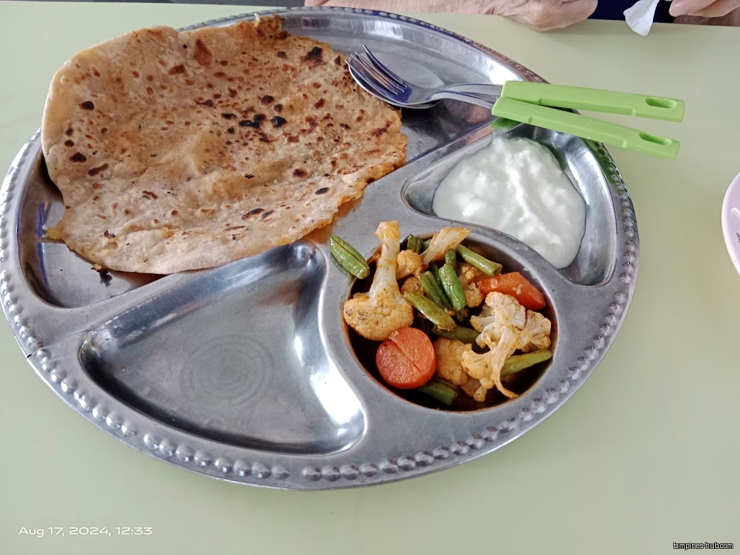 A metal plate with roti, vegetables, and yogurt is shown.
