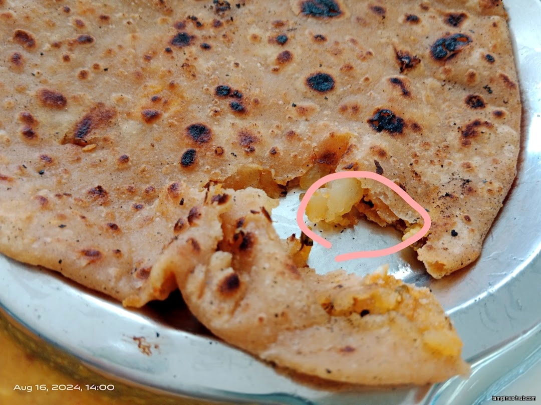 Close-up of a paratha with potato filling on a metal plate.