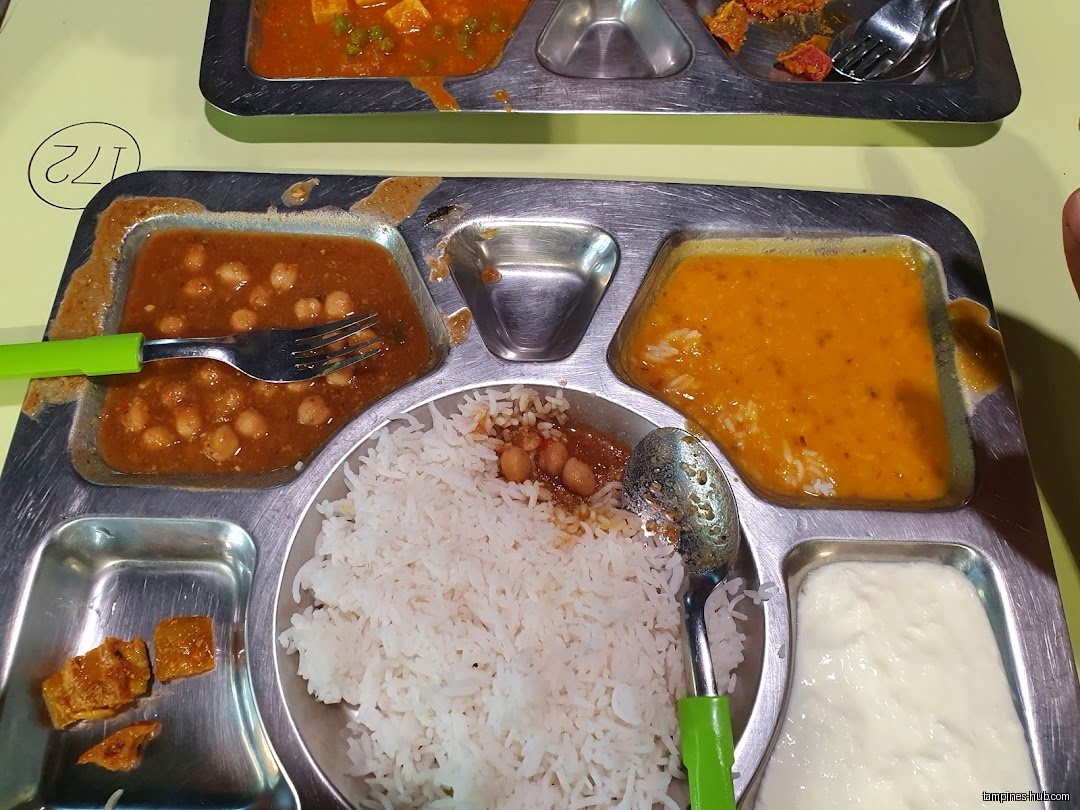 A metal tray holds rice, curry, yogurt, and other food items.