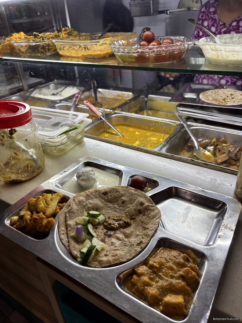 A metal tray with various Indian food items and a food display.