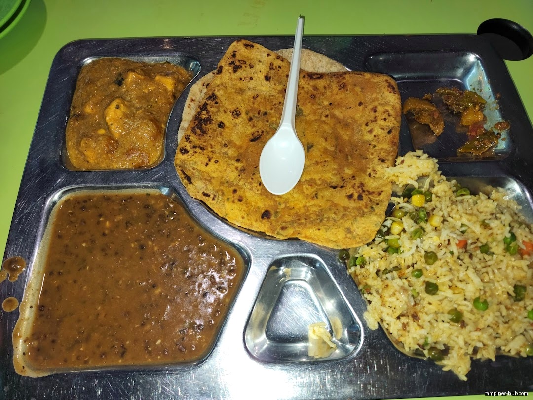 A metal tray holds Indian food, including roti, rice, and curries.