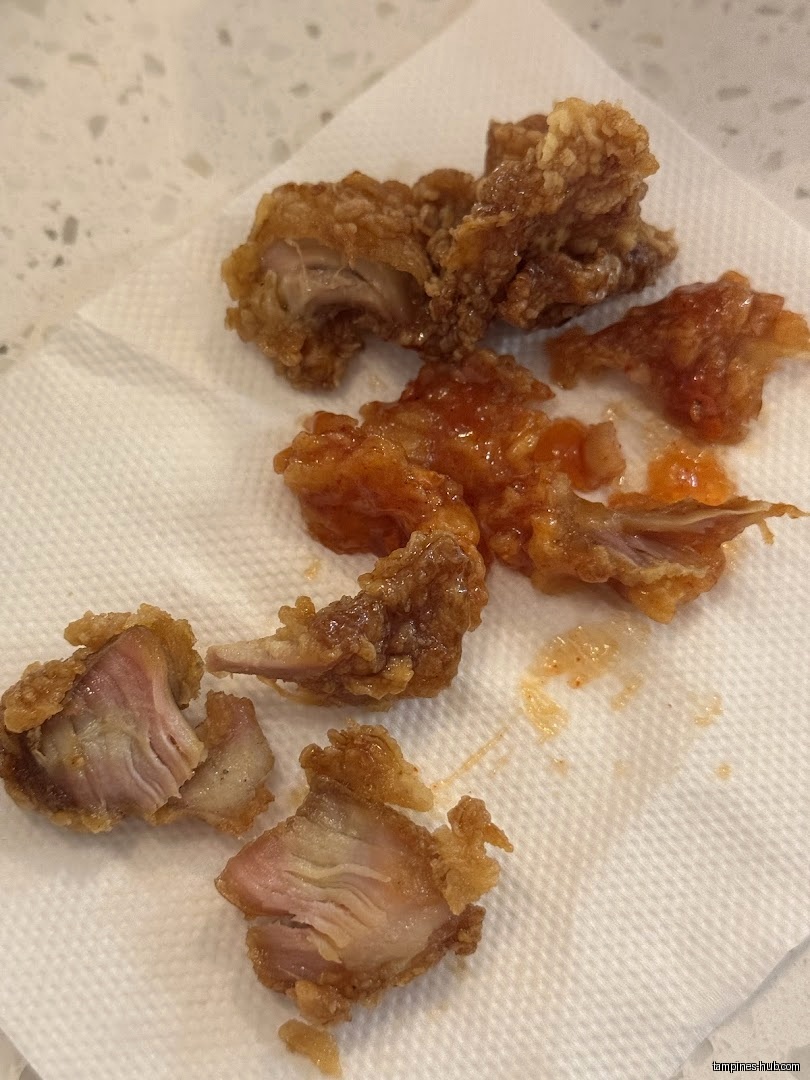 Close-up of fried chicken pieces, some with sauce, on a napkin.
