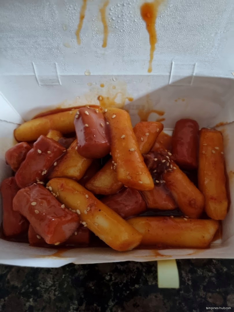 A close-up shot of tteokbokki and sausages in a white container.
