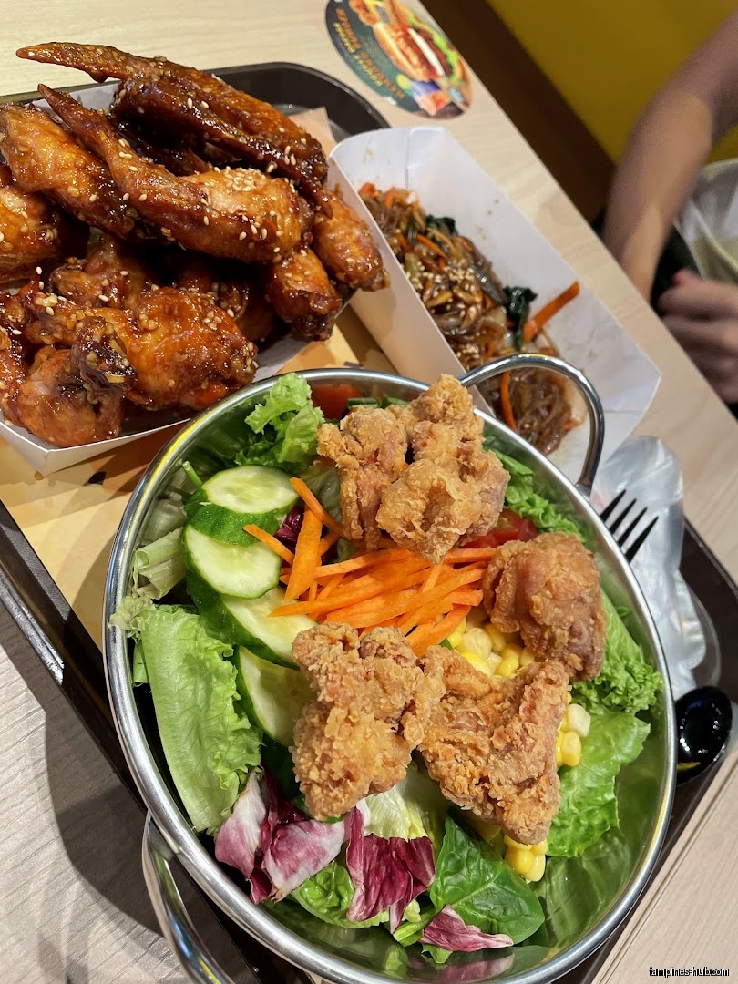 NeNe Chicken meal with chicken wings, salad, and japchae on a tray.