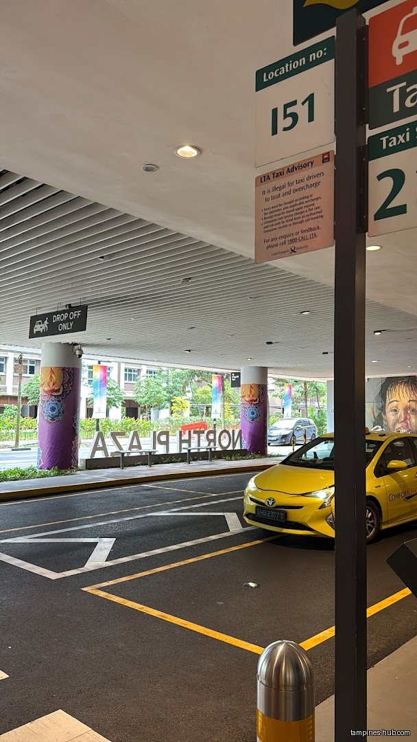 North Plaza drop-off point with taxi and location number sign.
