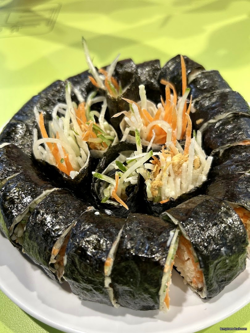 A plate of kimbap with shredded vegetables on top.